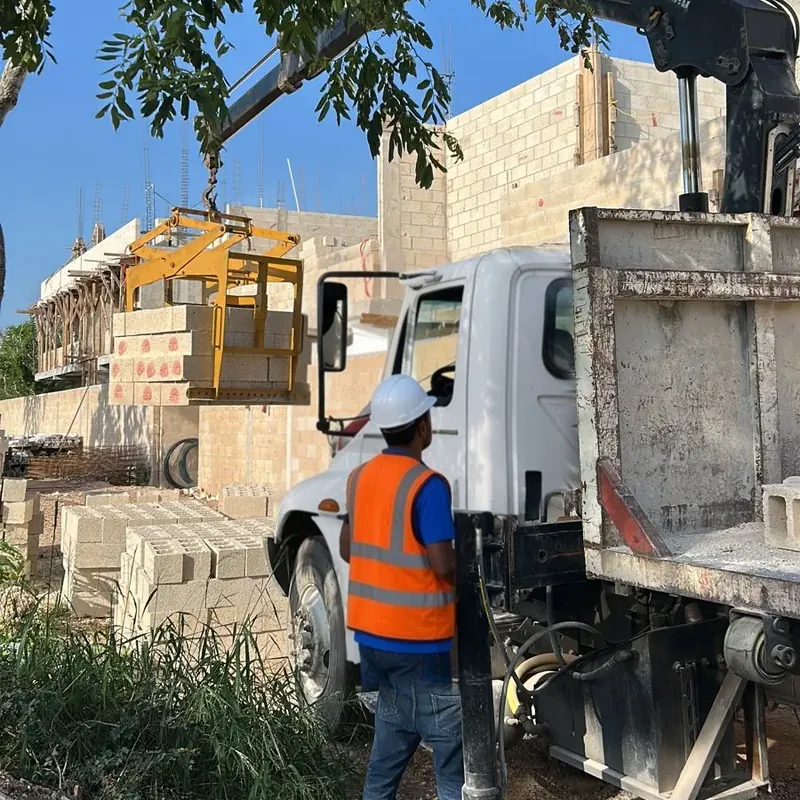 Camión con grúa descargando block en obra